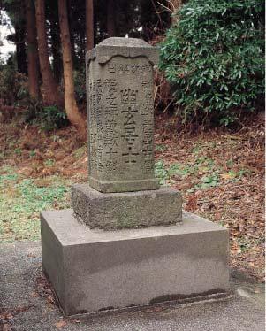文字が彫られた顕彰碑と、後ろに写る木々の写真