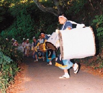 太鼓を持った和服の男性が山道で一列に並んでいる写真