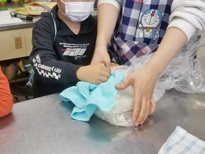 ごはんをだまこもちにする作業をする親子