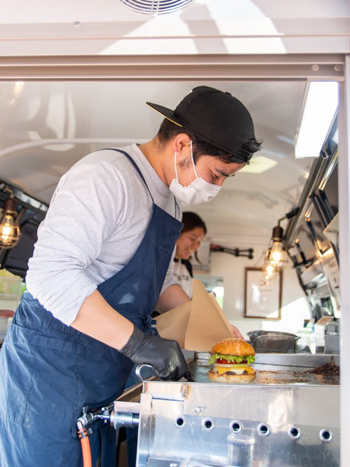 キッチンカーでハンバーガーを作る男性