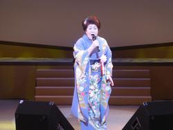 紫色の着物を着た女性が歌っている写真