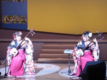 同じ袴を着た女性二人が舞台の上で三味線を弾いている写真