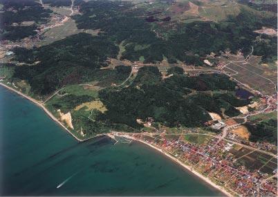海岸沿いに建っている民家や田畑、脇本城跡を上空から撮影した写真