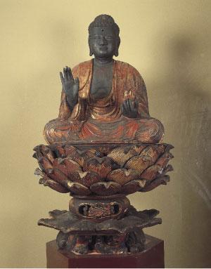 座禅を組み右手を挙げて左手は膝の上に手を置いた仏像の写真