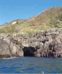 海の中にある岩場に大きな穴が開き空洞になっている洞窟の写真