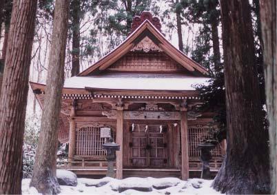 周囲には雪が積もっており、大きな杉の木の間に建っている木造の宮殿と宮殿の前に立っている2基の石灯籠の写真