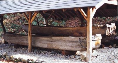 木で作られた屋根の下に、木で作られた細長い船が置かれている写真