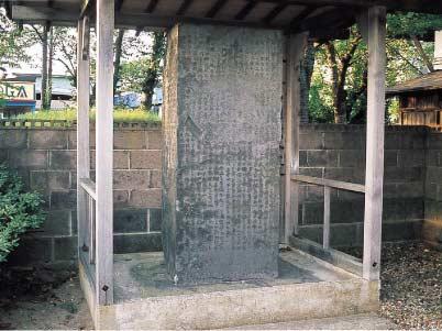 石の表面に沢山の文字が彫ってある村法碑が屋根付きの囲いの中に設置されている写真