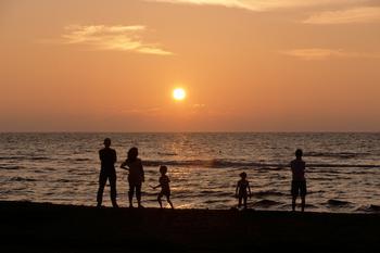 人々が海で夕陽を見ている写真