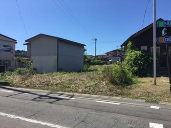 白い小屋と茶色の建物に囲まれた土地の写真